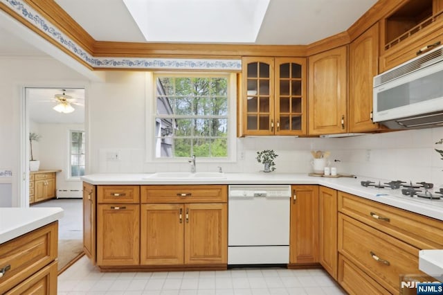 kitchen with a sink, light countertops, crown molding, and white appliances