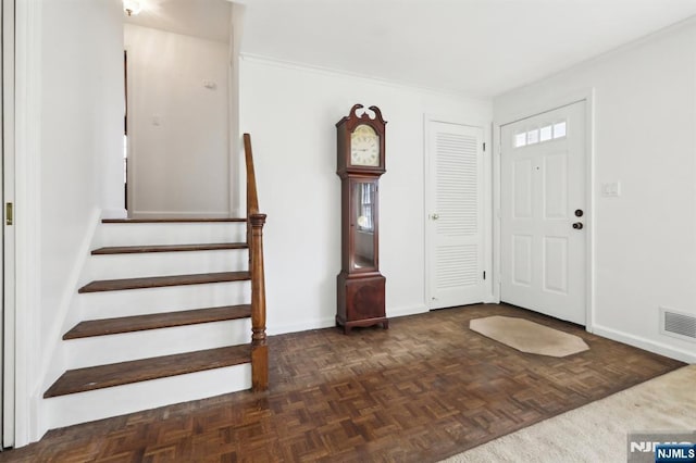 foyer entrance featuring baseboards, visible vents, and stairway