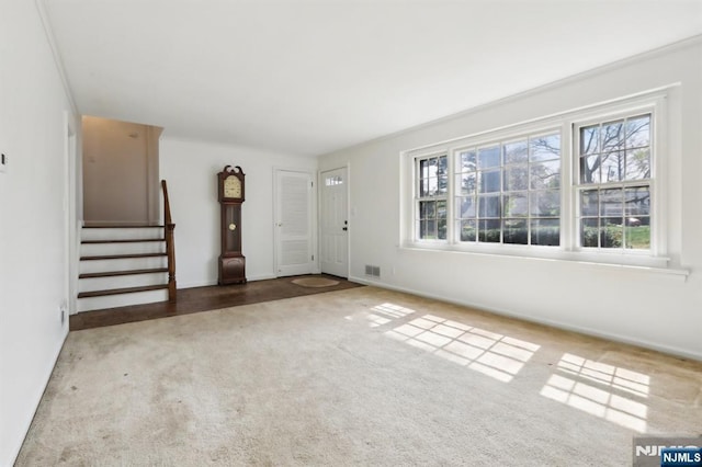 unfurnished living room with stairs, visible vents, plenty of natural light, and carpet