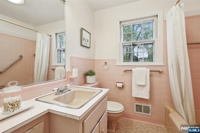 full bath with shower / bath combination with curtain, visible vents, tile walls, vanity, and toilet