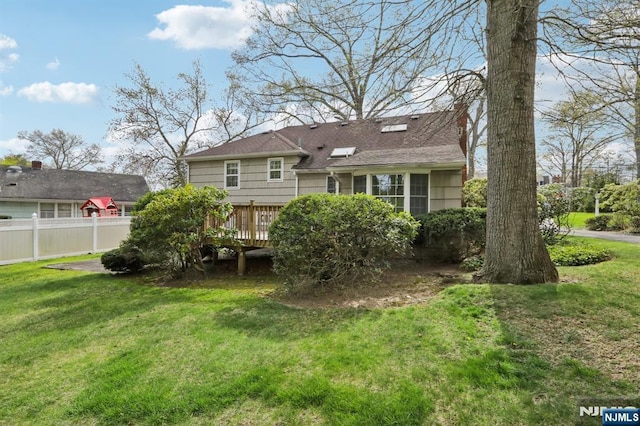 rear view of house featuring a yard, a deck, and fence