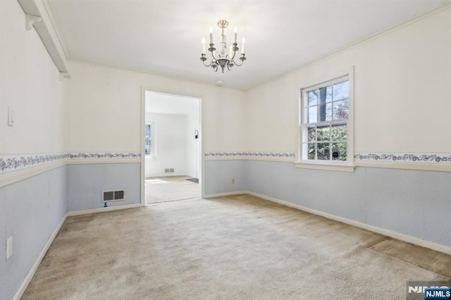 unfurnished room featuring visible vents, carpet floors, a wainscoted wall, and a chandelier