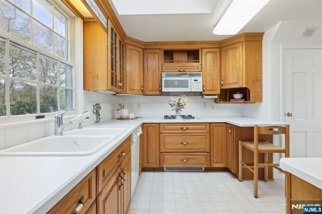 kitchen with visible vents, open shelves, a sink, glass insert cabinets, and white appliances