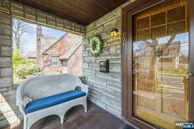 doorway to property with stone siding and covered porch