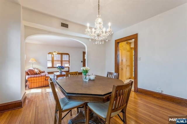 dining area featuring arched walkways, visible vents, baseboards, and light wood-type flooring