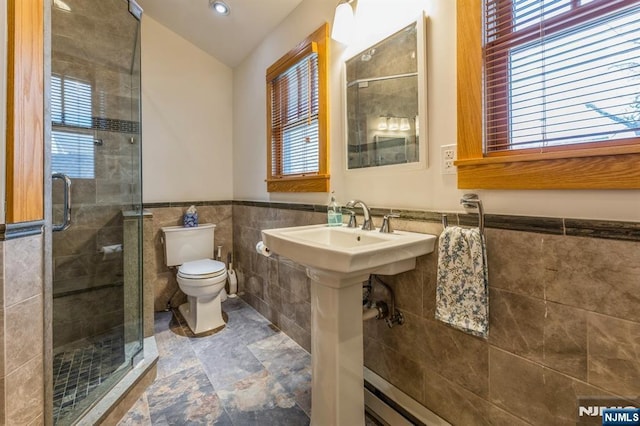 bathroom with a shower stall, toilet, recessed lighting, tile walls, and wainscoting