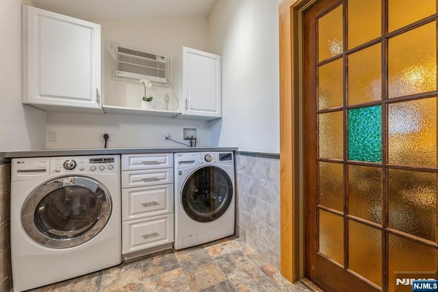 washroom with washer and dryer, cabinet space, stone finish floor, tile walls, and a wall mounted AC