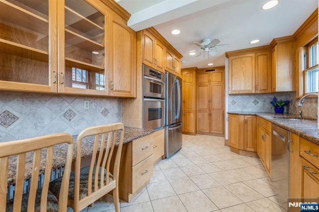 kitchen featuring dark stone countertops, recessed lighting, stainless steel appliances, a sink, and a ceiling fan