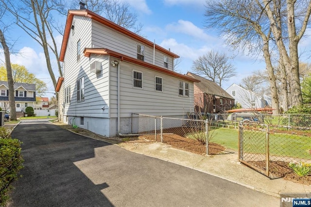 rear view of house with a gate, fence, and driveway