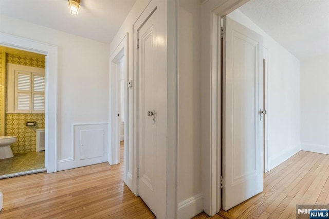 corridor featuring light wood-style floors and baseboards
