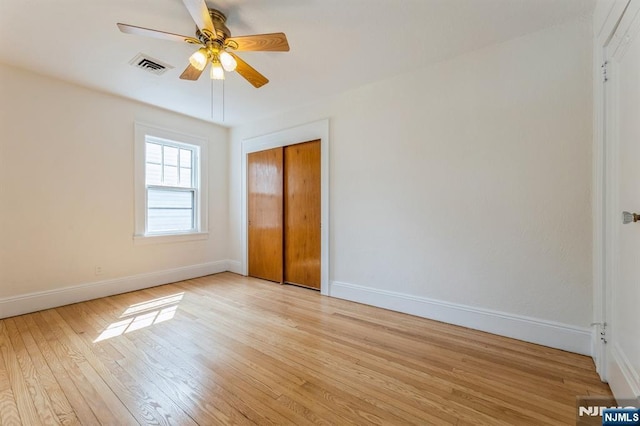 unfurnished bedroom featuring light wood-style flooring, visible vents, ceiling fan, a closet, and baseboards