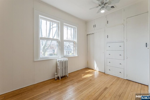 unfurnished bedroom featuring radiator, a closet, and light wood-style flooring