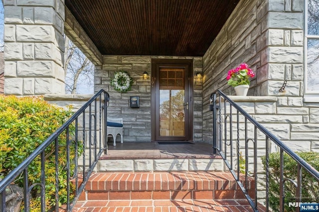 view of exterior entry with stone siding and covered porch