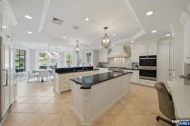 kitchen with a sink, tasteful backsplash, visible vents, custom range hood, and double oven