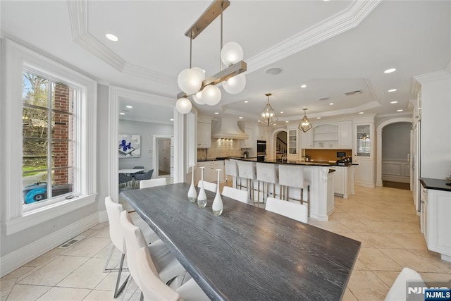dining space with light tile patterned floors, visible vents, arched walkways, and a raised ceiling