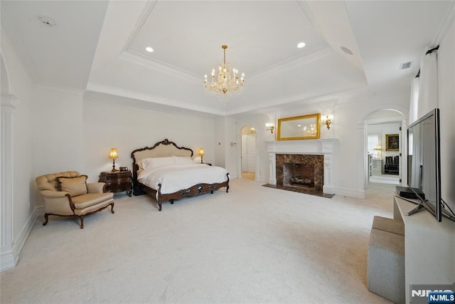 bedroom with arched walkways, a notable chandelier, light colored carpet, a premium fireplace, and a raised ceiling
