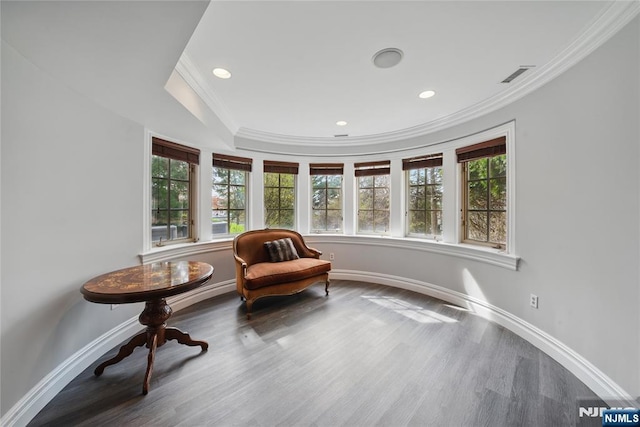 living area with baseboards, crown molding, wood finished floors, and visible vents