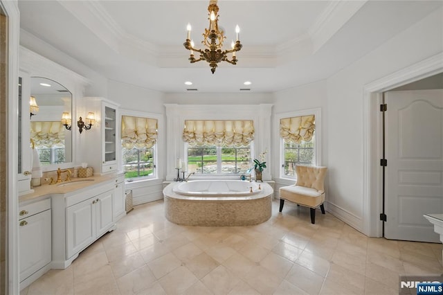full bathroom featuring a raised ceiling, a garden tub, vanity, and an inviting chandelier