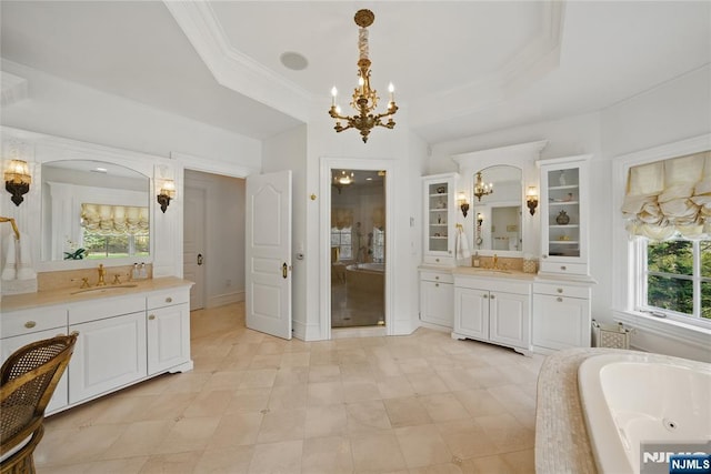bathroom with a sink, a chandelier, a raised ceiling, and a tub with jets
