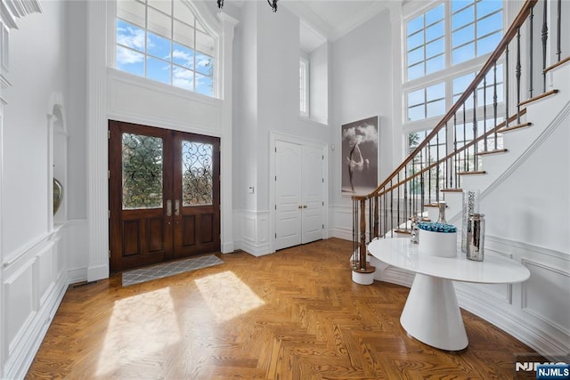 foyer entrance with a decorative wall, ornamental molding, stairs, and a high ceiling