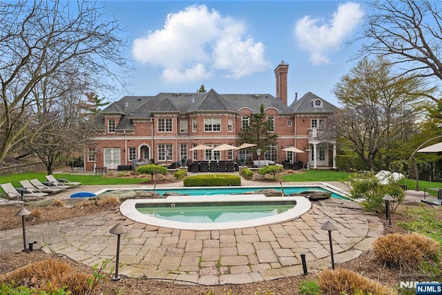 pool featuring a patio and an in ground hot tub