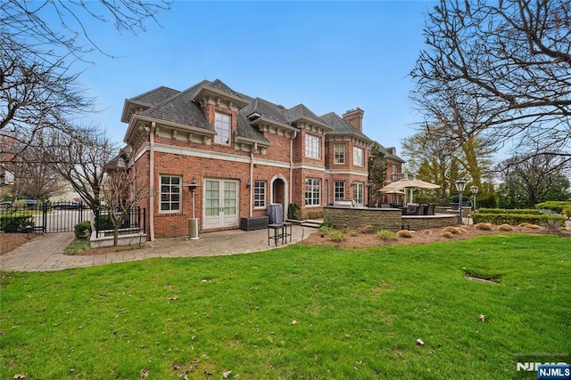 rear view of property with a gate, fence, a patio area, a lawn, and brick siding