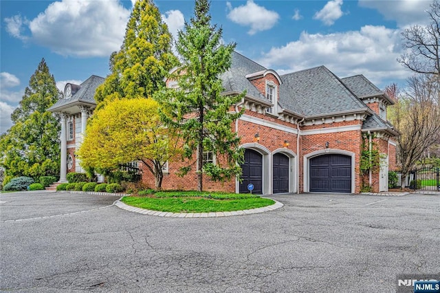 view of front of property featuring brick siding, an attached garage, driveway, and fence
