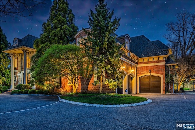 view of front facade with fence, aphalt driveway, brick siding, and a garage