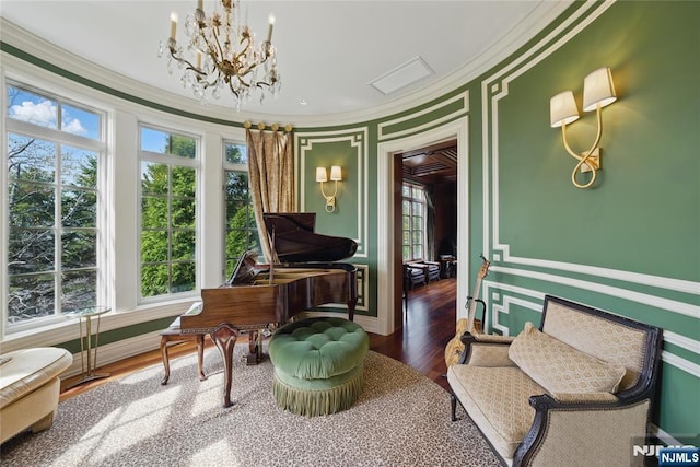 sitting room with an inviting chandelier, crown molding, wood finished floors, and a healthy amount of sunlight