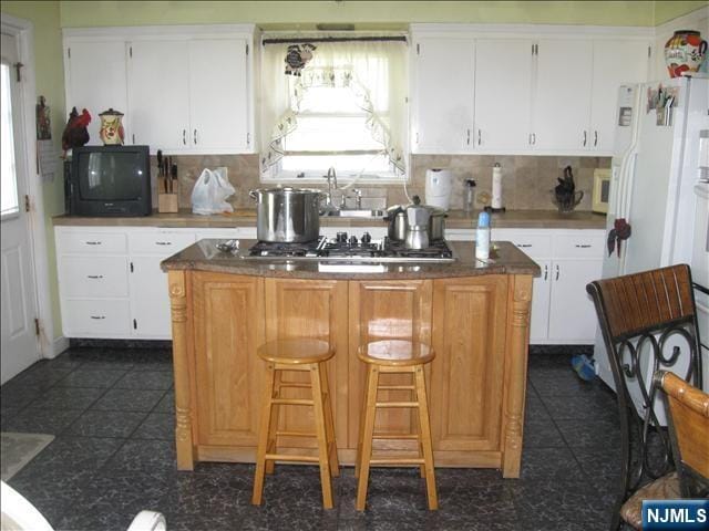 kitchen with tasteful backsplash, dark tile patterned flooring, and a kitchen island