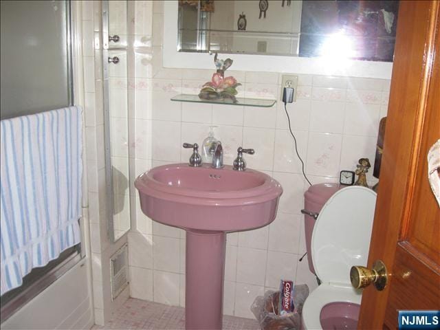 bathroom featuring a shower, tile walls, and toilet