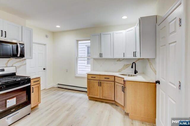 546 Morris St, Orange, NJ 07050 - kitchen featuring gas range, light countertops, a sink, a baseboard radiator, and light wood finished floors