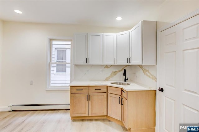 546 Morris St, Orange, NJ 07050 - kitchen featuring a sink, a baseboard radiator, light countertops, light wood finished floors, and backsplash