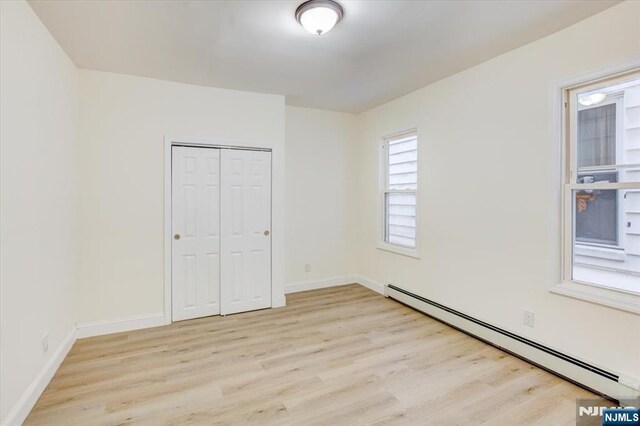 546 Morris St, Orange, NJ 07050 - unfurnished bedroom featuring a closet, a baseboard radiator, light wood finished floors, and baseboards