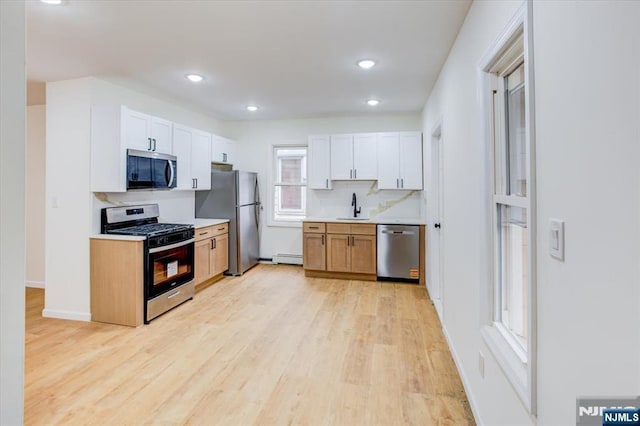 546 Morris St, Orange, NJ 07050 - kitchen featuring light wood-type flooring, light countertops, backsplash, stainless steel appliances, and a sink