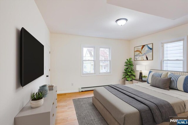 546 Morris St, Orange, NJ 07050 - bedroom featuring a baseboard heating unit, light wood-style flooring, multiple windows, and baseboards