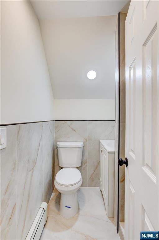 546 Morris St, Orange, NJ 07050 - bathroom with tile patterned floors, a baseboard radiator, tile walls, and toilet