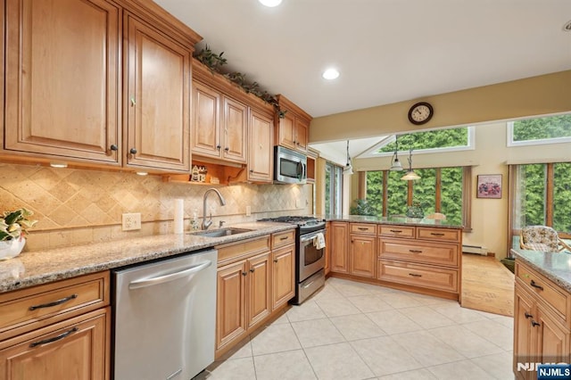 kitchen featuring appliances with stainless steel finishes, a sink, a peninsula, light tile patterned floors, and light stone counters
