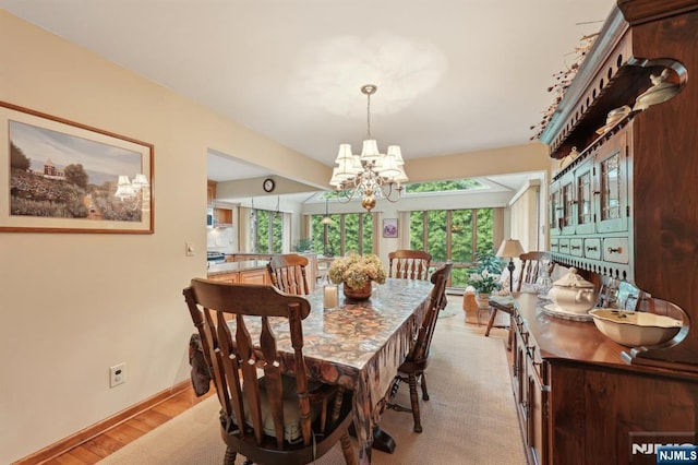 dining area featuring a chandelier, light wood finished floors, and baseboards
