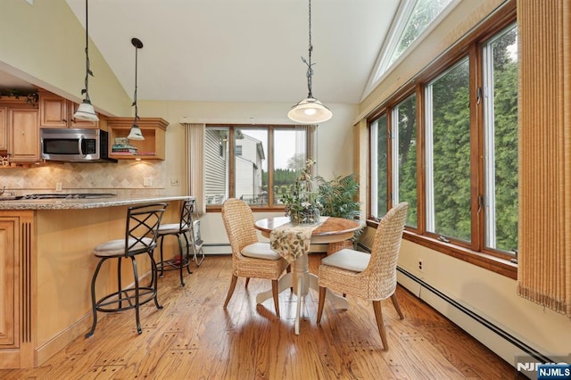 dining space featuring lofted ceiling, a baseboard heating unit, and light wood-style flooring