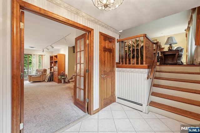 foyer featuring baseboard heating, stairway, track lighting, a chandelier, and light colored carpet