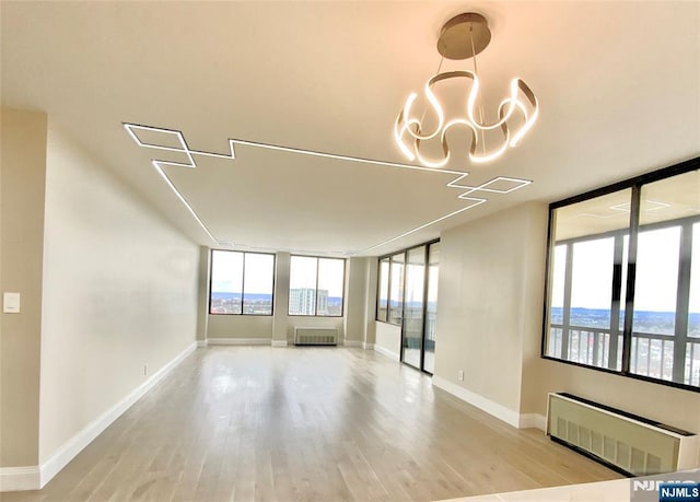 300 Winston Dr Unit 1722, Cliffside Park, NJ 07010 - unfurnished room featuring radiator heating unit, a notable chandelier, light wood-type flooring, and baseboards