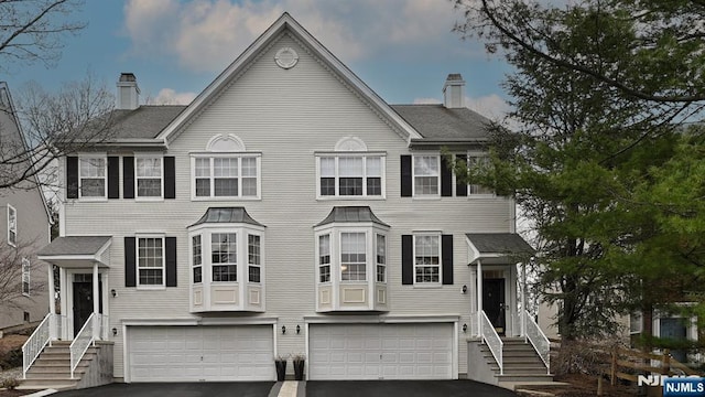 view of front facade featuring driveway, a chimney, and an attached garage