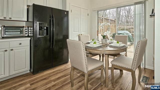 dining area featuring visible vents, light wood finished floors, and a toaster