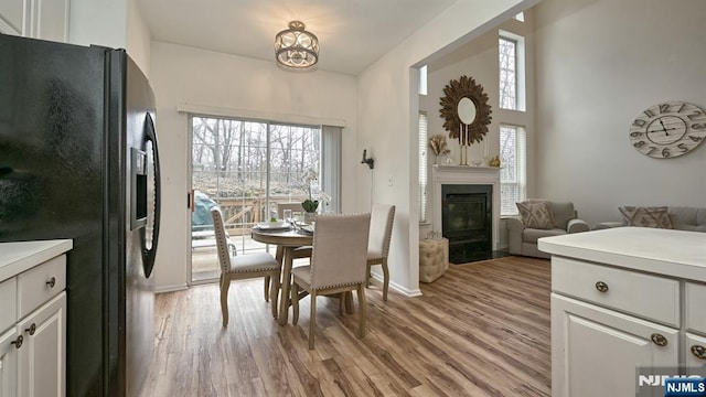 dining area featuring a wealth of natural light, a fireplace with flush hearth, light wood-style flooring, and baseboards