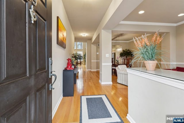 entryway featuring ornamental molding, baseboards, and light wood-style floors