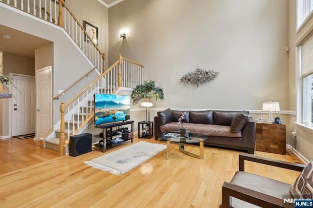 living room with wood finished floors, a towering ceiling, and plenty of natural light
