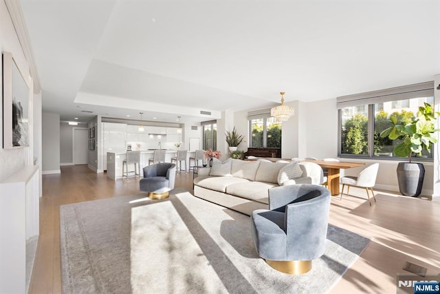 living area featuring visible vents, baseboards, an inviting chandelier, and wood finished floors