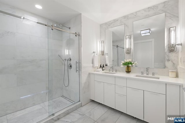 bathroom featuring a stall shower, double vanity, marble finish floor, and a sink
