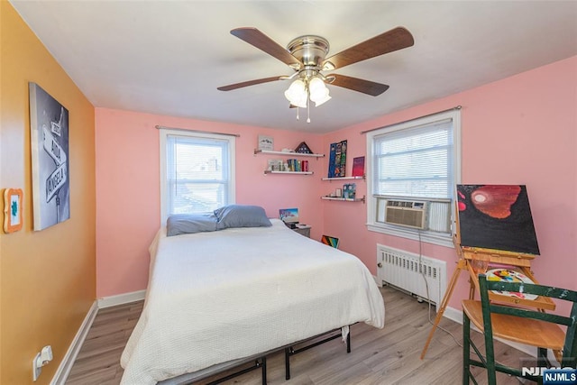 bedroom with radiator heating unit, light wood-type flooring, cooling unit, and baseboards